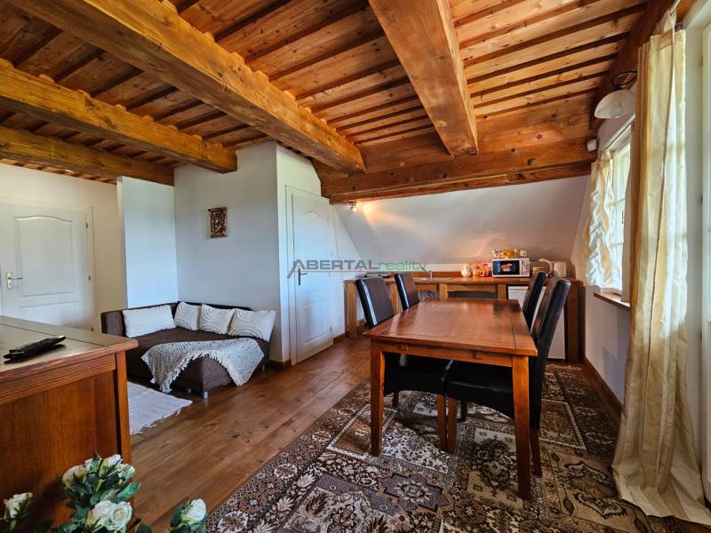 Wooden ceiling and table in the dining room of the family house with a sofa and decorations.