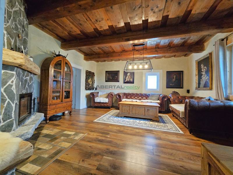 Living room in a family house with a fireplace, wooden ceiling, and comfortable sofas.