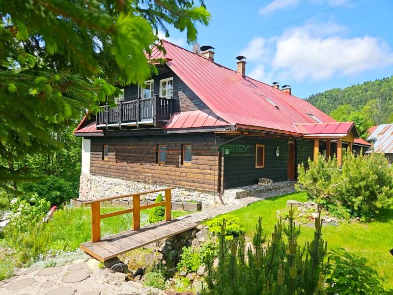 A family house in Donovaly with a wooden facade and a red roof in a natural environment.