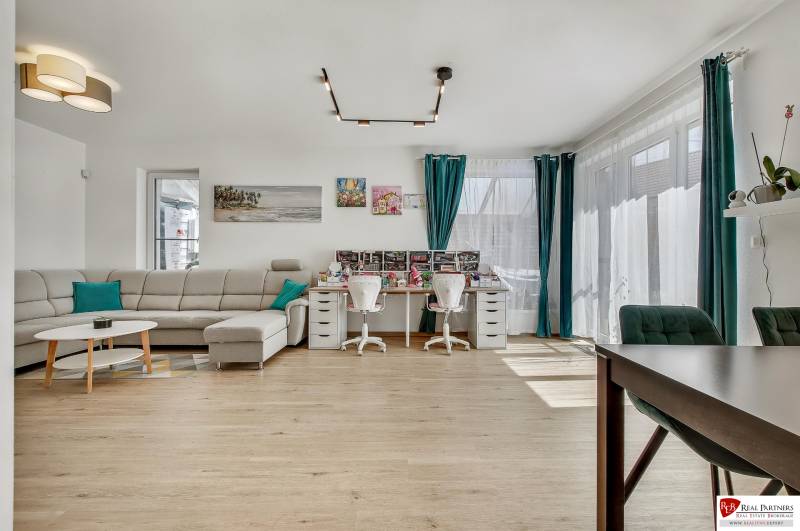 Living room with a sofa and a desk in a family house, bright room with windows.