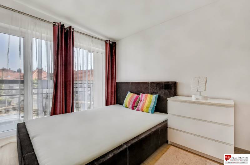 A bedroom in a family house with a bed and a dresser, complemented by colorful pillows.