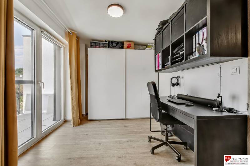 A workspace in a family house with a large window, a desk, a chair, and storage spaces.