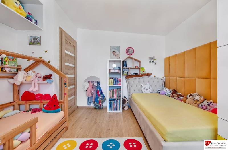 Children's room in a family house with beds, shelves, and toys, light wooden floors.