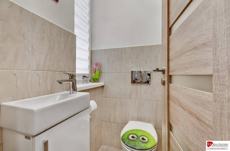 Bathroom in a family house with a toilet and decorative ceramic tiles.