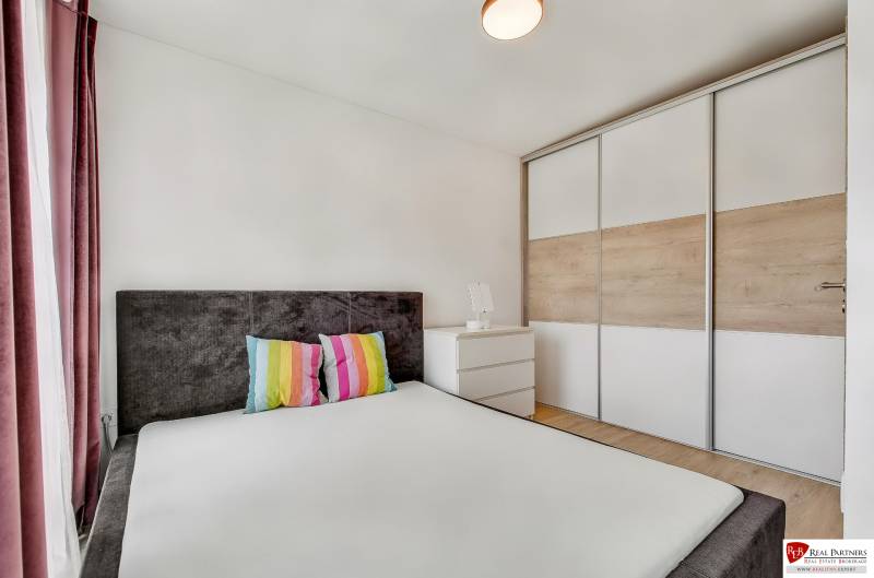 A bedroom in a family house with colorful pillows and a built-in wardrobe.