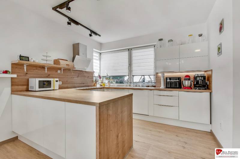 A kitchen in a family house with white cabinets, a wooden countertop, and kitchen appliances.
