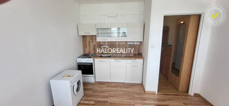 A kitchen in a studio apartment with a stove, dishwasher, and cabinets, wooden floor.