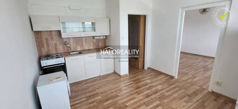 Kitchen unit in a studio apartment with wooden flooring and white cabinets.