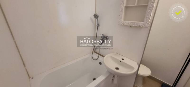Bathroom in a studio apartment with a bathtub, mirror, and sink.