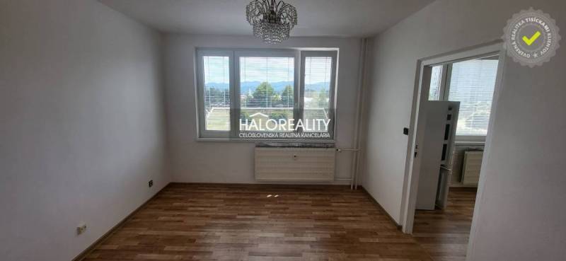 A room in a one-bedroom apartment with a wooden floor and a view from the window.