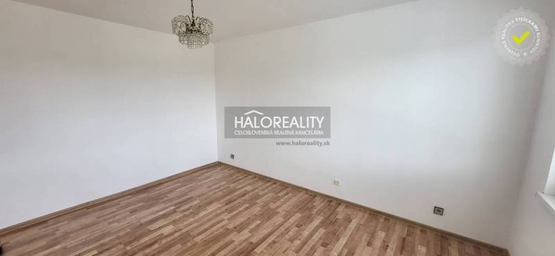 An empty room in a one-room apartment with a parquet floor and a ceiling light.