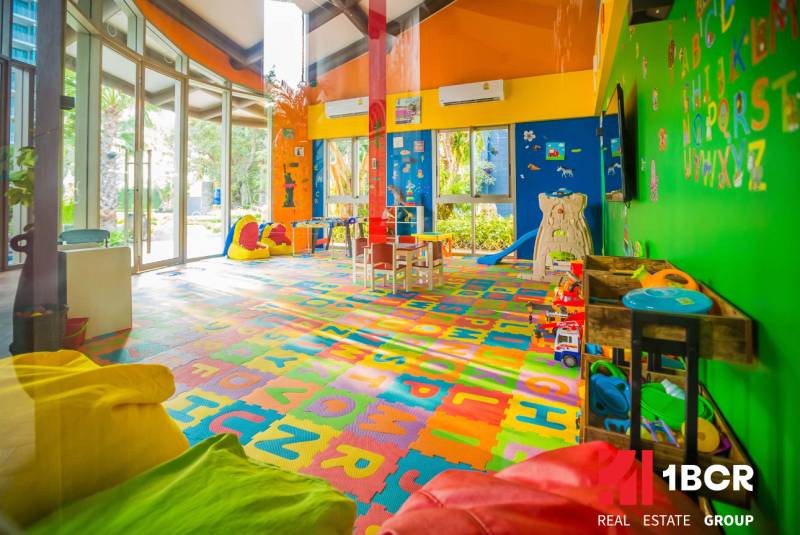 A colorful indoor playground under construction in an apartment building with toys and tables.