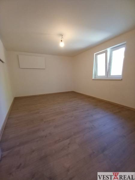 Empty room with laminate flooring and white walls in a family house.