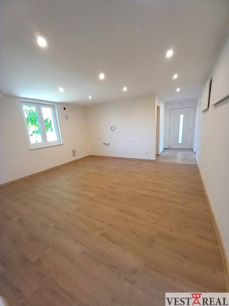 A spacious room with laminate flooring and spotlights in a family house.