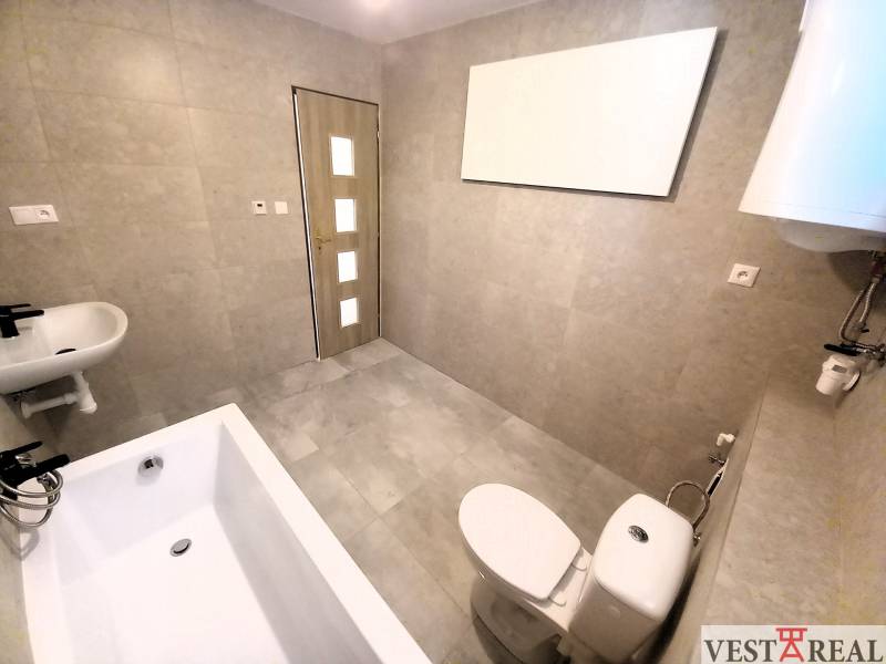 Bathroom in a family house with a bathtub, sink, and toilet, light tiles.