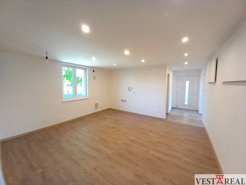 A spacious living room in a family house with wooden flooring and white walls.
