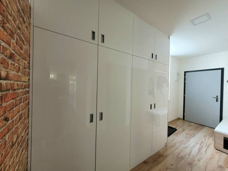 Entrance hallway in a 3-room apartment with white cabinets and brick cladding.
