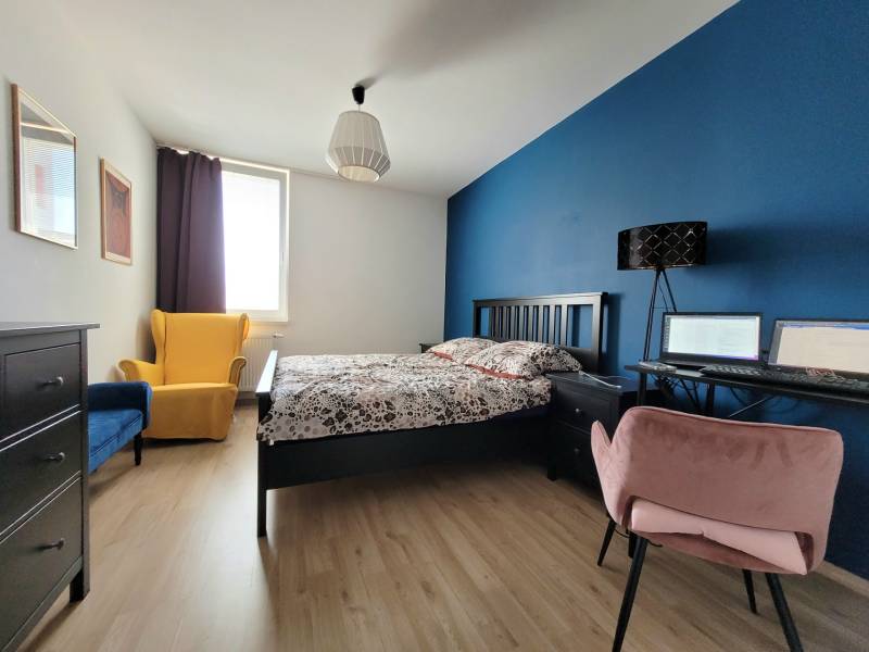 A bedroom in a 3-room apartment with colorful chairs and a work corner.