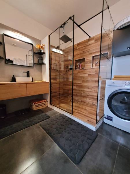 Bathroom in a 3-room apartment with a wooden shower and a washing machine.