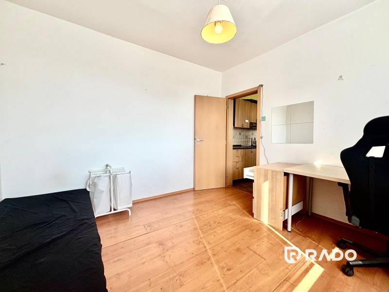 A room with a wooden floor, a black chair, a table, and baskets in a 3-room apartment.
