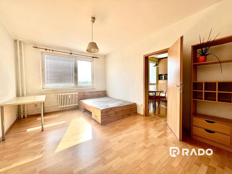 A room in a 3-room apartment with light furniture, a bed, and a large window.