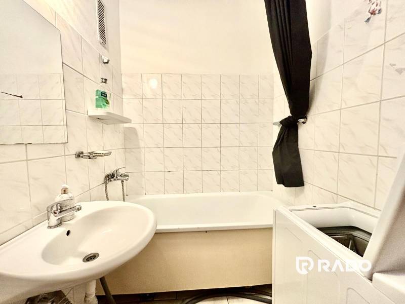 A bathroom with a bathtub, sink, and washing machine in a 3-room apartment.