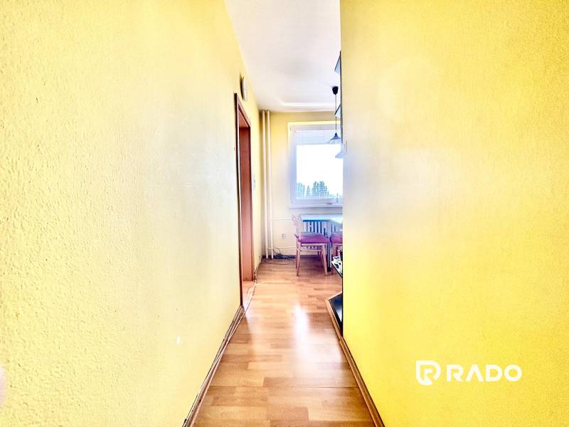 The yellow hallway leads to a bright kitchen in a three-room apartment.
