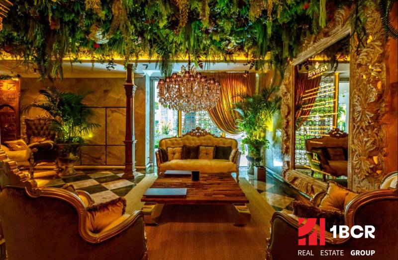 Luxurious living room with a chandelier, plants, and golden curtains as part of apartment construction.