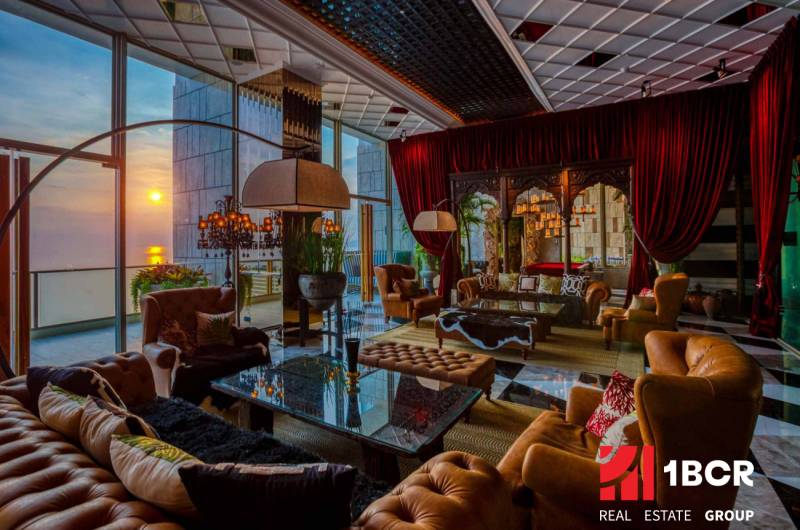 Luxury living room interior with leather furniture and a sunset view.