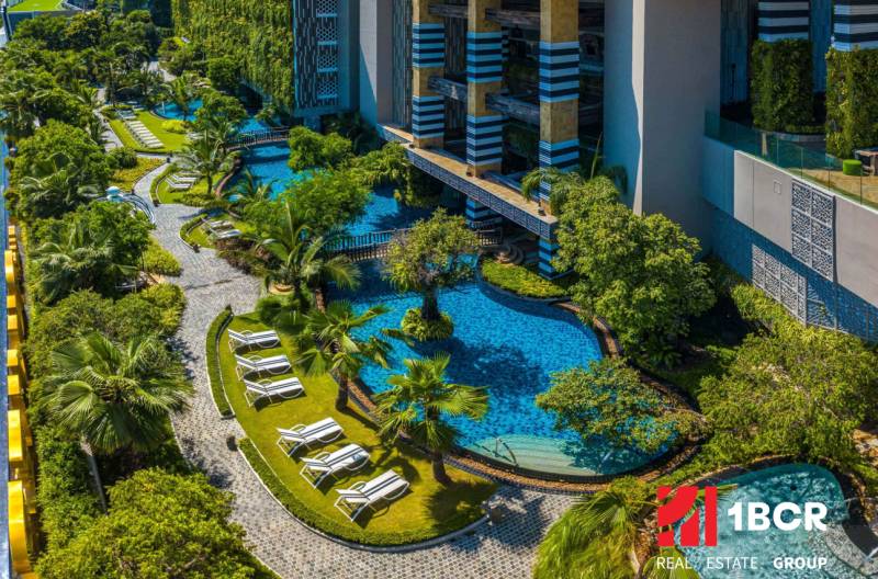 A swimming pool surrounded by greenery and walkways in a residential development in Pattaya.
