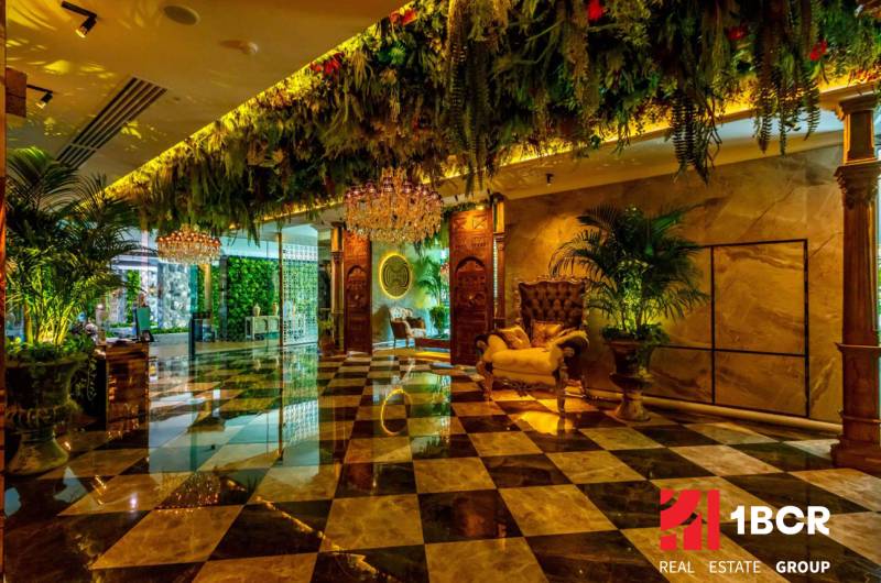 Luxurious interior with a chandelier, green decorations, and patterned flooring. Apartment construction.