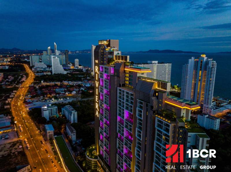 Night panorama of Pattaya with apartment construction by the coast, illuminated high-rise buildings.