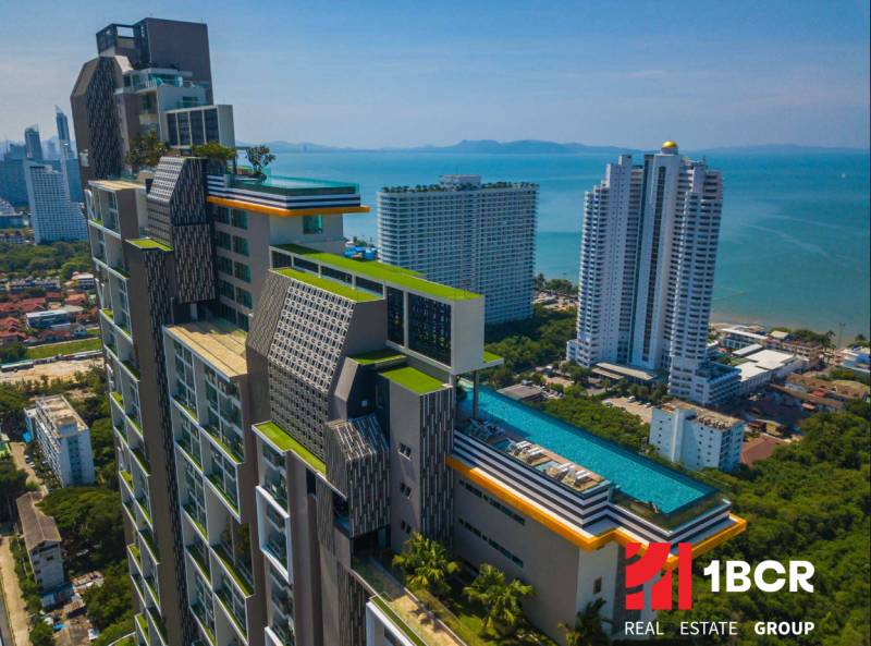 Apartment construction in Pattaya with a rooftop pool and panoramic views of the coastline.