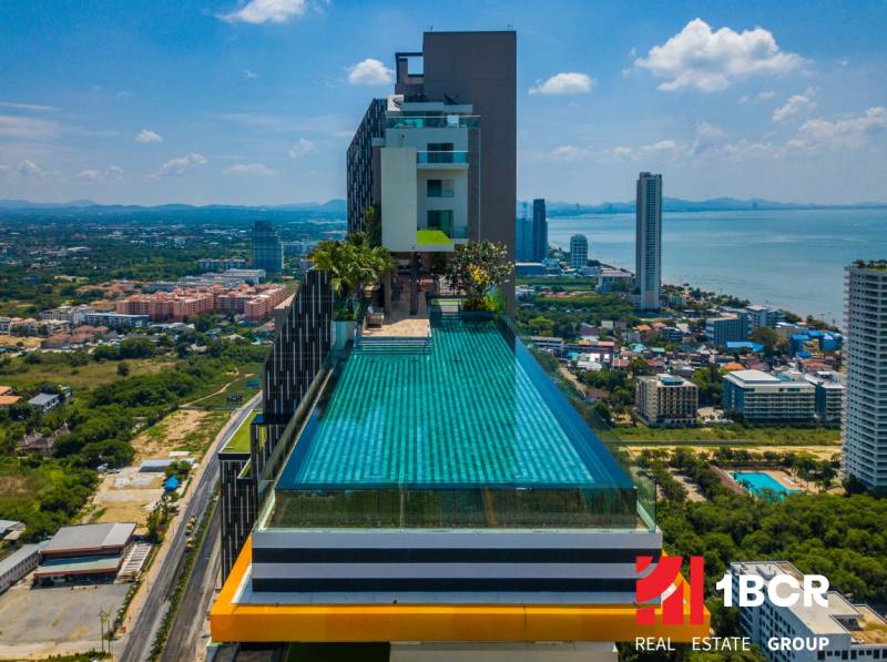 Apartment construction in Pattaya with a rooftop pool and sea view.