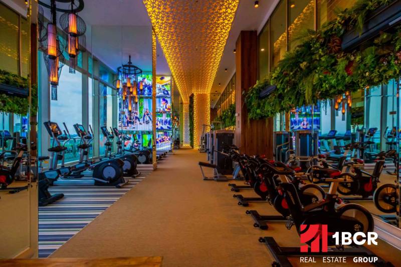 The interior of a gym under construction in an apartment building with lighting and exercise equipment.
