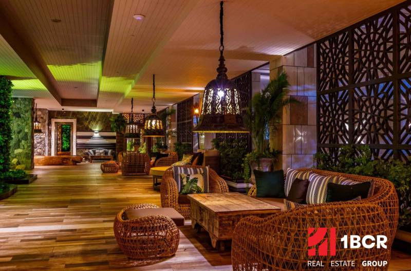 Interior of residential building with comfortable rattan furniture and decorative lighting.
