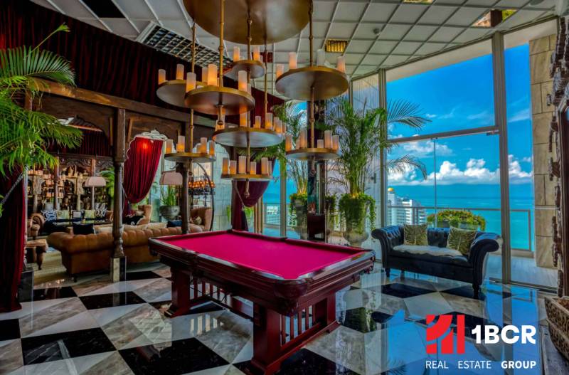 Luxury interior with a pool table, large windows, and an ocean view. Apartment construction.