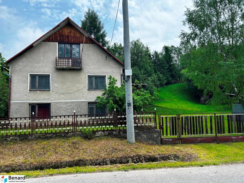A family house in Veľká Lesná with a landscaped garden and lawn, surrounded by trees.