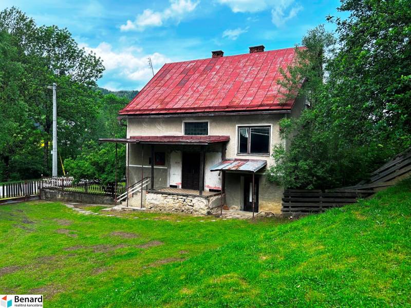 A family house in Veľká Lesná with a red roof and a garden surrounded by greenery.