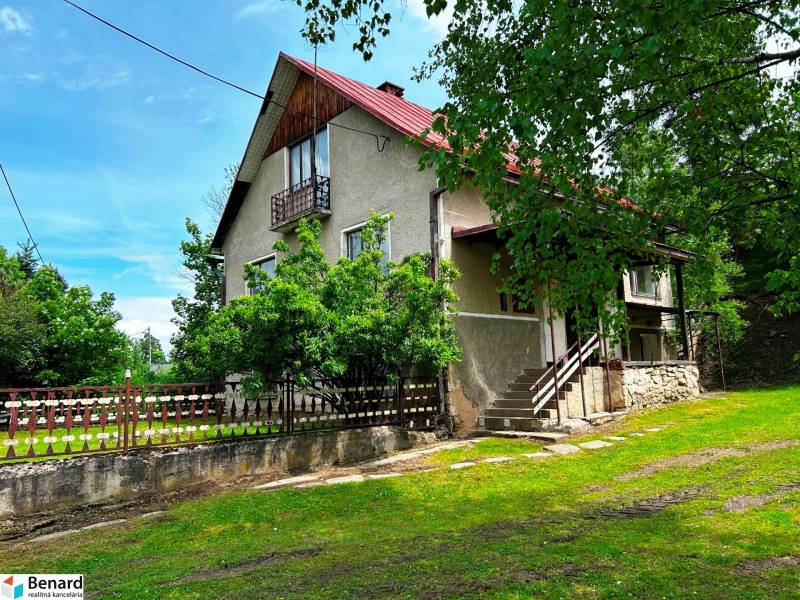 A family house in Veľká Lesná surrounded by greenery and a wooden fence.