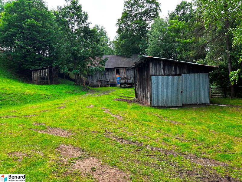 A family house in Veľká Lesná with a wooden shelter surrounded by greenery and trees.