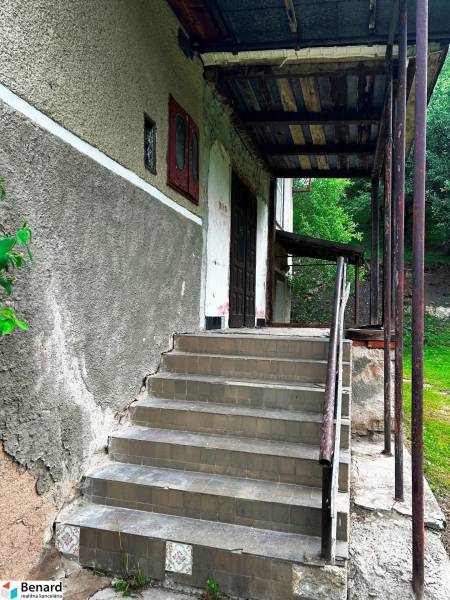 Entrance with a staircase to a family house in Veľká Lesná, surrounded by green vegetation.