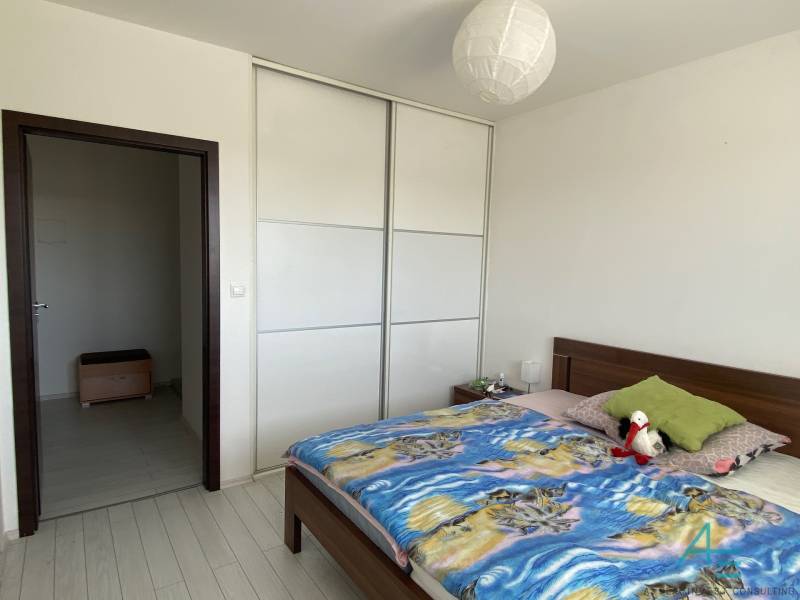 Bedroom with a double bed, built-in wardrobe, and lamp in a 3-room apartment.