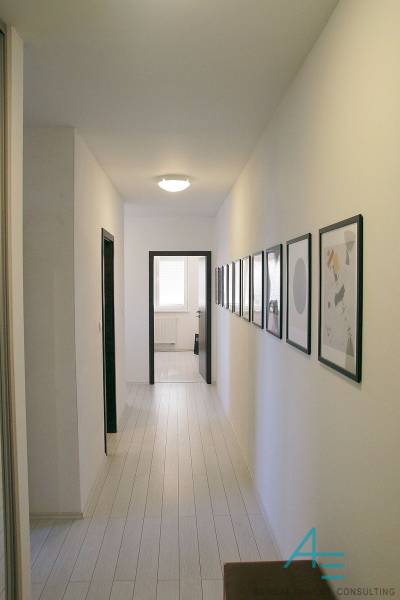 A hallway in a 3-room apartment with light floors and pictures on the walls.