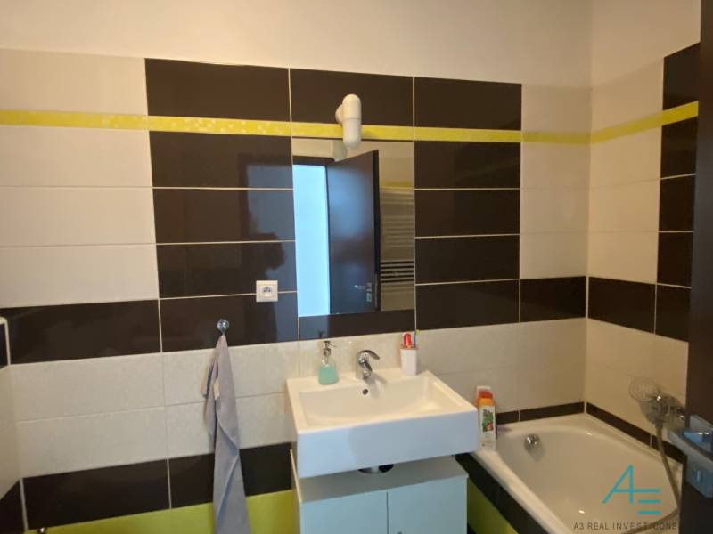 Bathroom in a 3-room apartment with a shower, sink, and light-colored tiles.