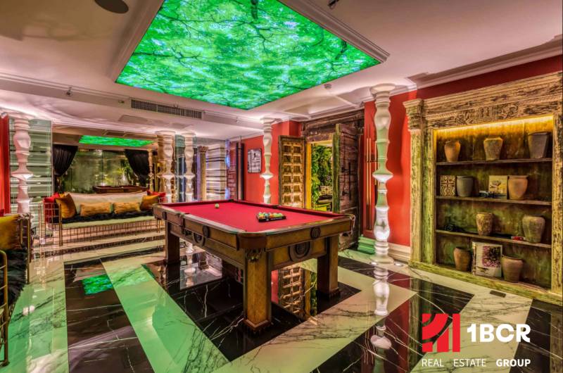 Luxury interior with a billiard table, green elements, and decorations within the construction of apartments.
