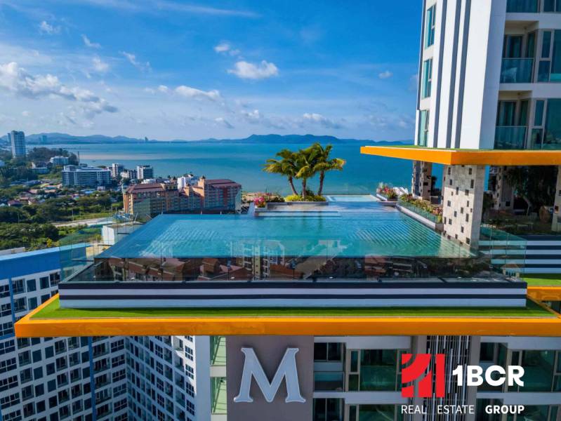 Apartment construction in Pattaya with a rooftop pool and sea view.