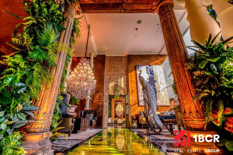Luxurious interior with a chandelier, decorative columns, and greenery in the construction of apartments.