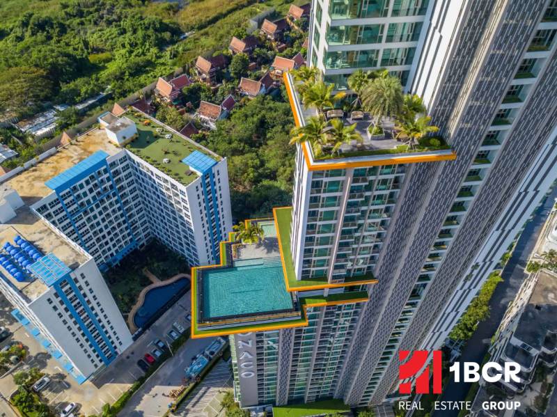 The construction of apartments in Pattaya features a high-rise building with a pool and a rooftop garden.