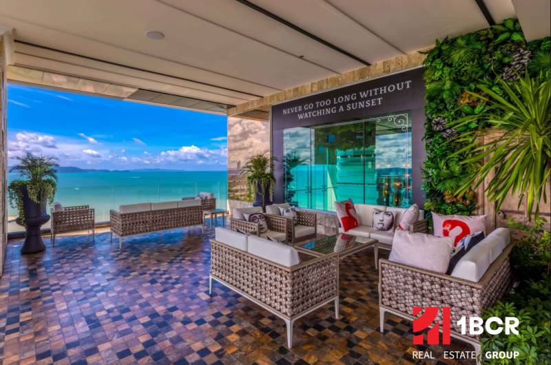 Apartment construction with terrace and sea view in Pattaya, comfortable seating and greenery.